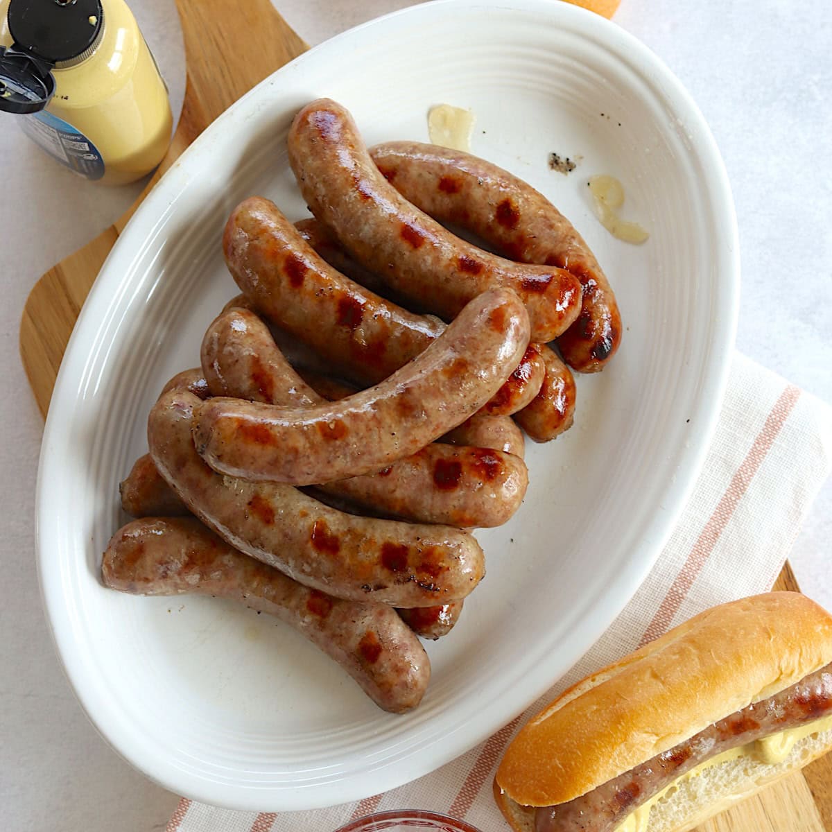 Beer brat crockpot recipe served in a stack on a white oval platter.