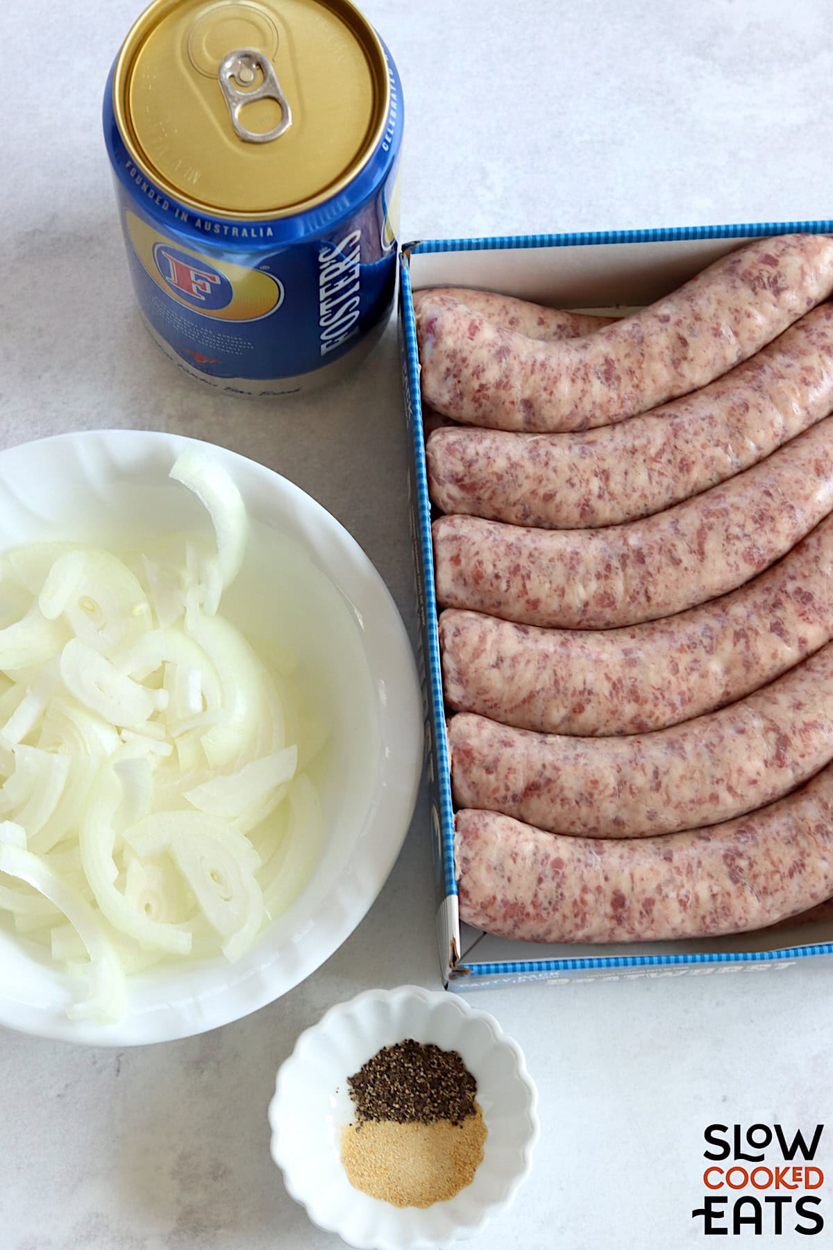 Ingredients needed to make beer brats crockpot recipe on a white marble countertop.