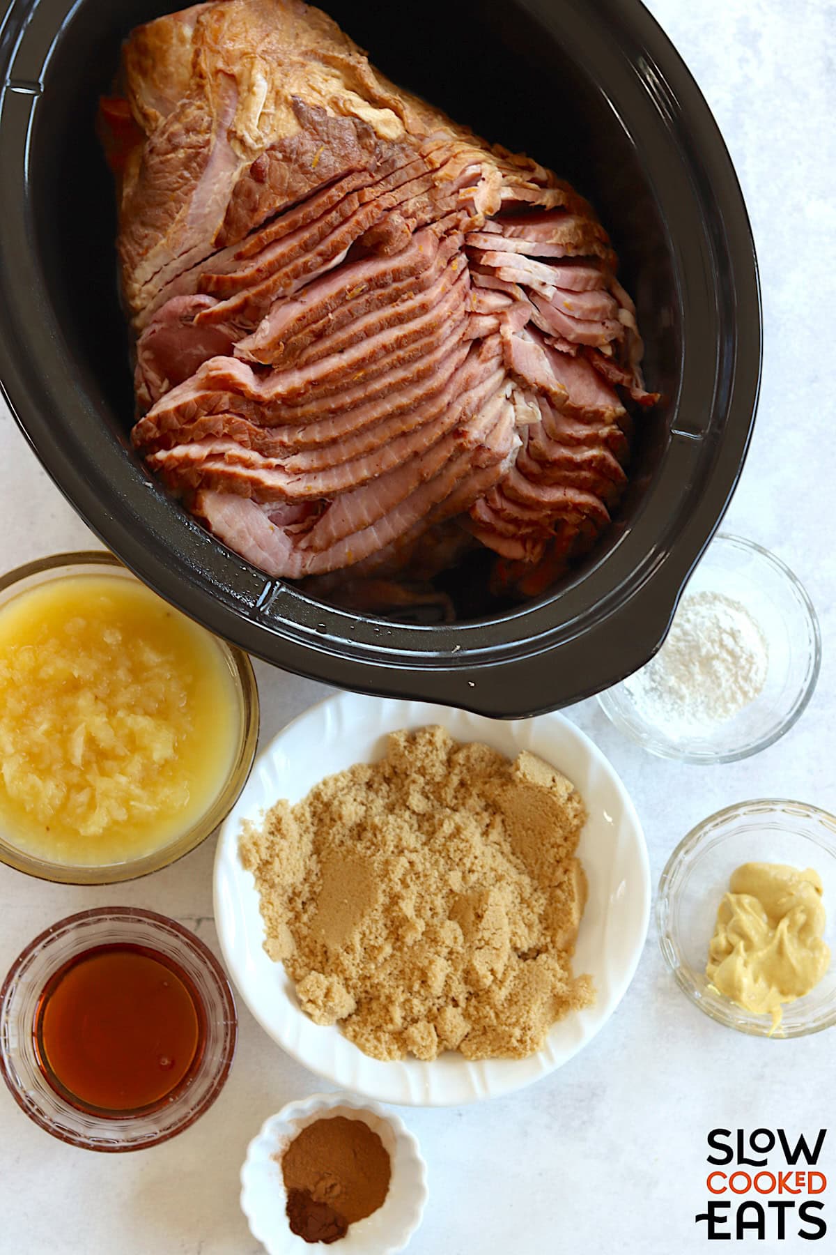 Ingredients needed to make pineapple crockpot ham on a white marble countertop.