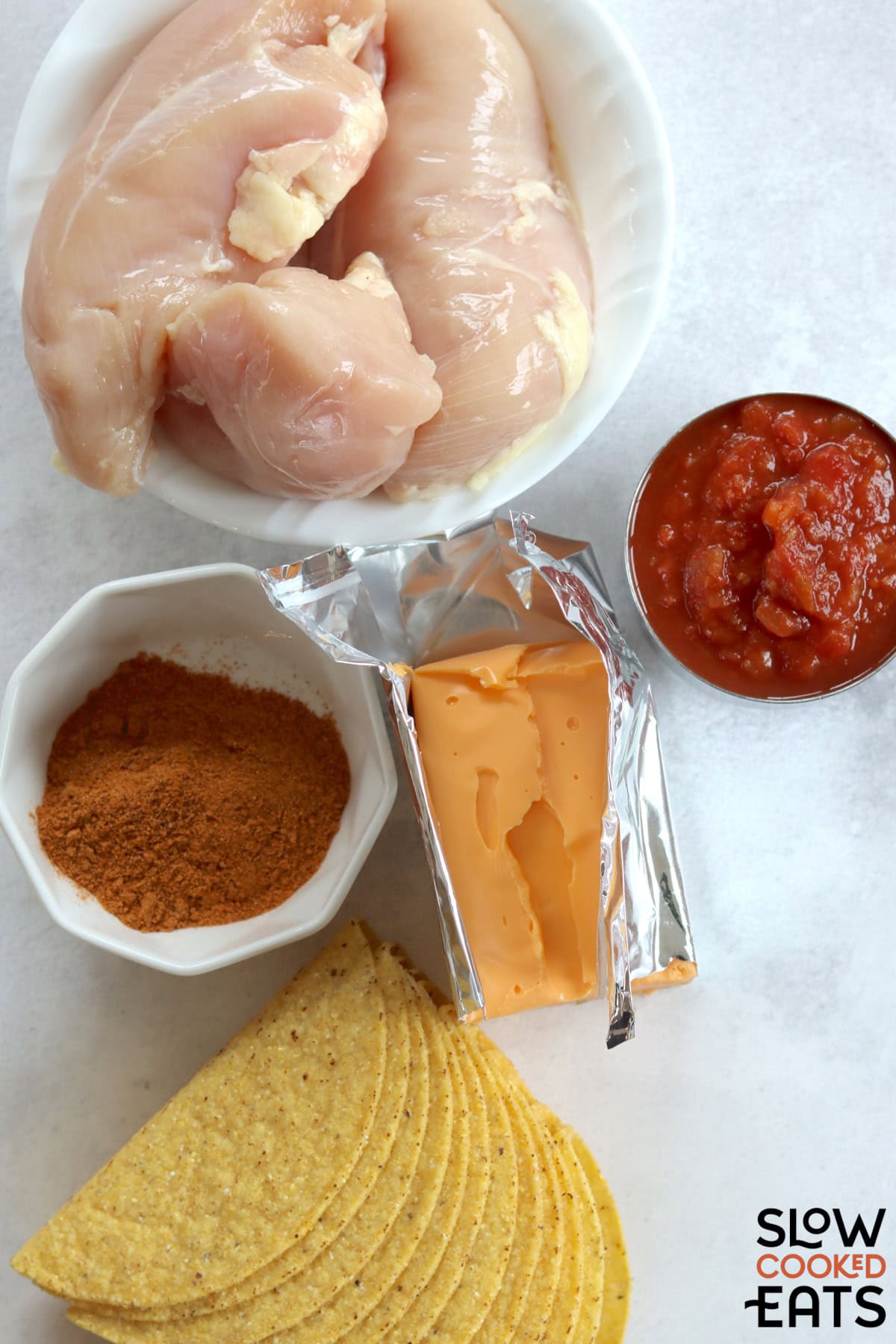 Ingredients needed to make the best slow cooker queso chicken tacos on a white marble countertop.