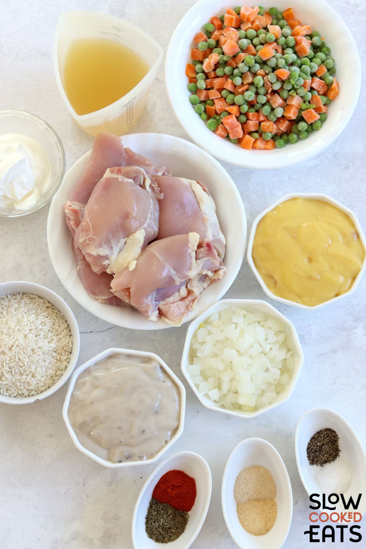 Ingredients needed to make crock pot chicken thighs and rice on a white marble countertop.