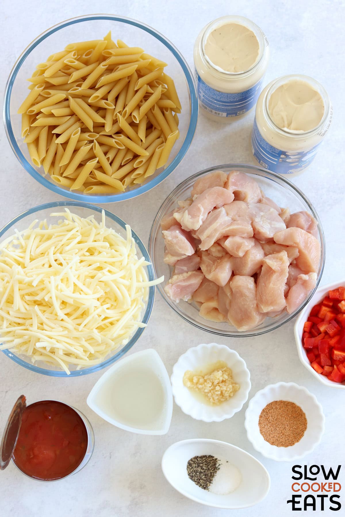 Ingredients needed to make crockpot Cajun chicken alfredo on a white marble countertop.