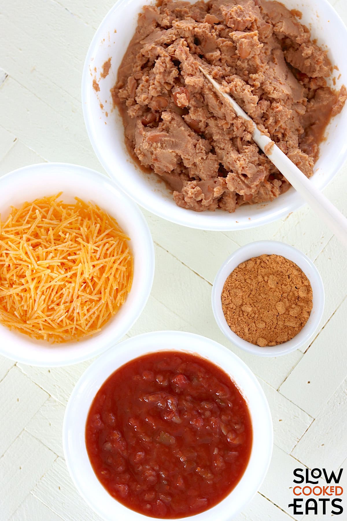 Ingredients needed to make slow cooker refried beans on a white marble countertop.