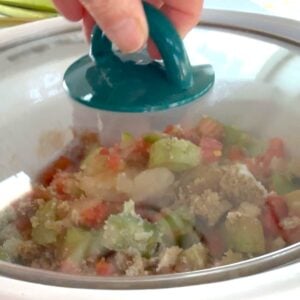 Placing the crockpot lid on the pot to cook the slow cooker rhubarb sweet chili jam.