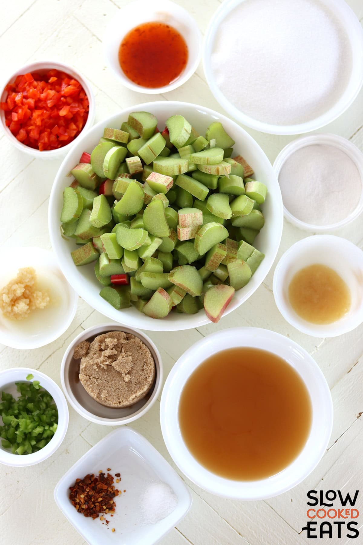 Ingredients needed for making slow cooker rhubarb sweet chili jam on a white wooden board.